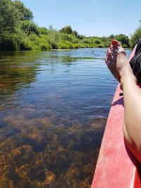 Low section of person on lake by trees