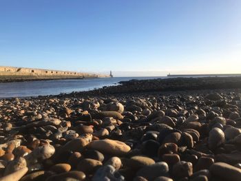 Stones on beach against clear sky