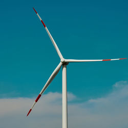 Wind turbine in front of a blue sky with white clouds