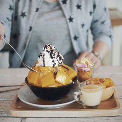 Midsection of woman eating dessert on table