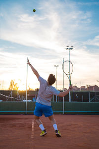 Full length of young man playing tennis on field