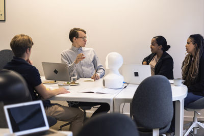 Business people discussing robot voice assistant during meeting