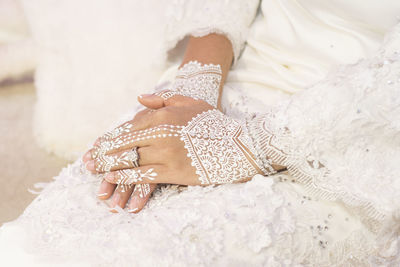 Midsection of bride with tattoo on hand