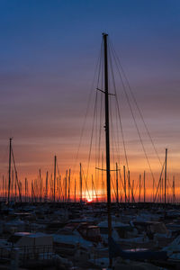 Sailboats moored at harbor during sunset