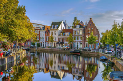 Canal by buildings against sky in city