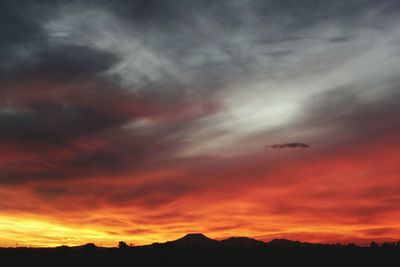 Scenic view of mountains against cloudy sky at sunset