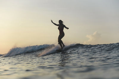 Young woman surfing at sunset