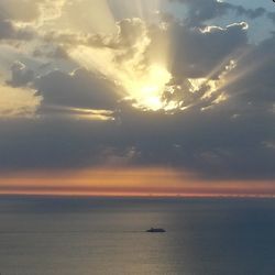 Scenic view of sea against cloudy sky during sunset