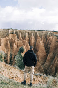 Rear view of man on rock against sky