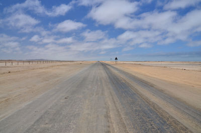 Tire tracks on desert against sky