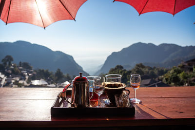 Close-up of teapot with glass in tray on table against sky