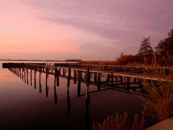 Pier over lake against sky during sunset