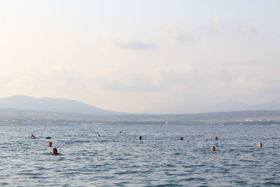 People swimming in sea against sky