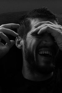Close-up of man laughing against black background