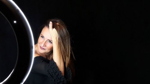 Smiling mature woman looking away against black background