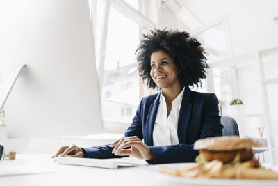 Young businesswoman working with hamburger on her desk