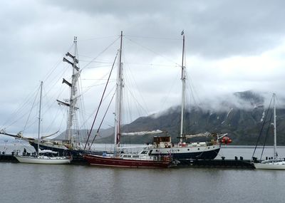 Sailboats moored in sea against sky