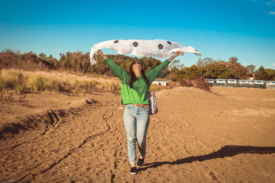 Full length of happy woman standing against sky