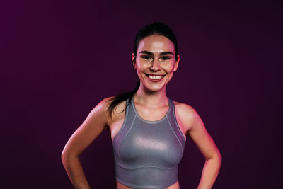 Portrait of young woman standing against black background