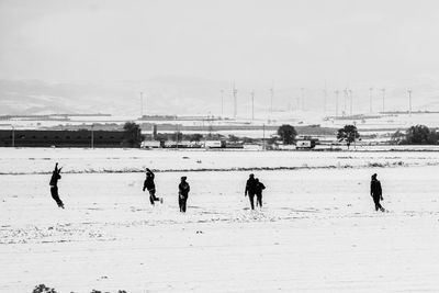 Playful friends on snow covered playground against sky