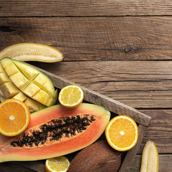 Fresh tropical fruits in a wooden delivery box on wooden background. papaya, orange, banana, coconut