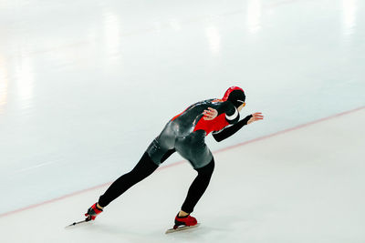 Man in sports uniform ice skating at rink