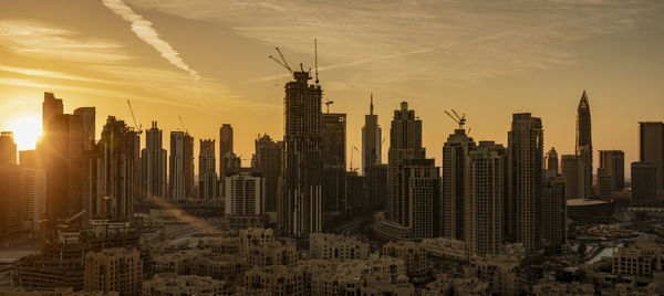 Modern buildings in city against sky during sunset