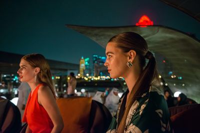 Portrait of smiling young woman in illuminated city at night