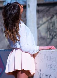 Rear view of fashionable woman standing by against wall