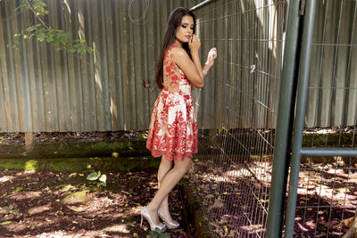 Full length portrait of woman standing against wall