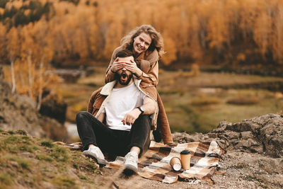 A happy couple in love a man and a woman are traveling walking hiking in the autumn forest in nature