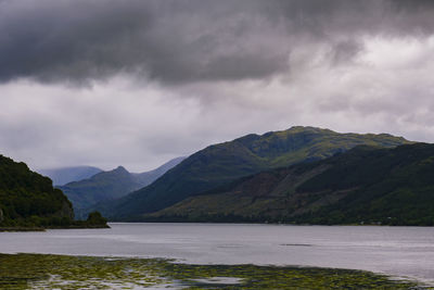 Scenic view of lake and mountains against cloudy sky