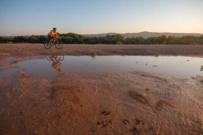 Man riding bicycle on land against sky