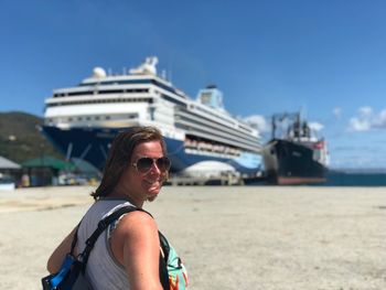 Portrait of woman wearing sunglasses at beach against sky