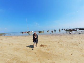 Man walking on beach against sky