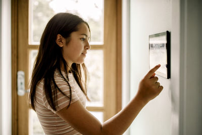 Side view of girl using home automation through tablet pc mounted on wall