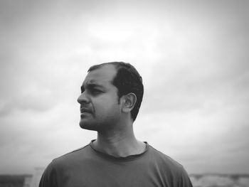 Portrait of young man looking away against sky