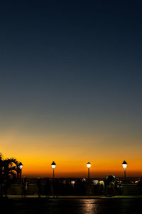 Silhouette of people and lampposts, at sunset, in tome de souza square