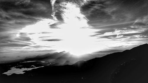 Sun shining through clouds over sea