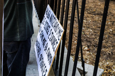 Man standing by railing against fence