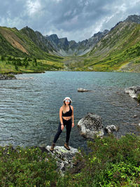 Full length of woman standing on rock by lake