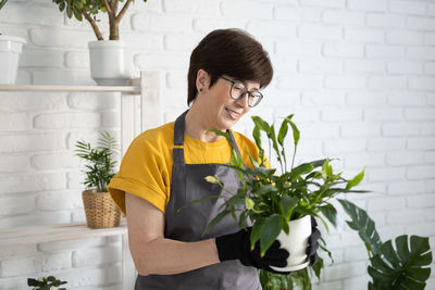 Side view of young woman holding potted plant