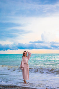 Woman standing at beach against sky