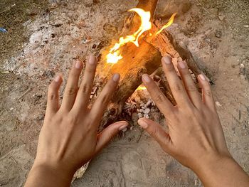 Cropped image of hand above bonfire at beach