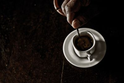 Cropped hand stirring coffee on table