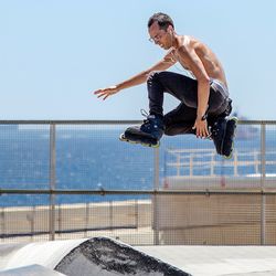 Low section of man skateboarding on skateboard against sky