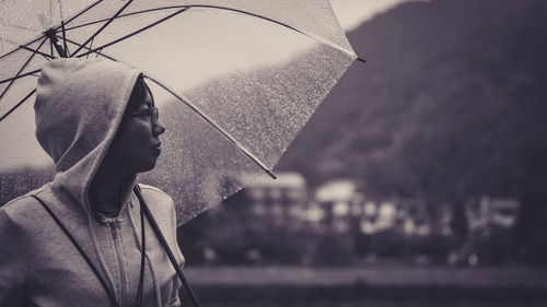 Young woman with umbrella standing in rain