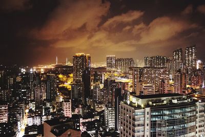 Illuminated cityscape against cloudy sky at dusk