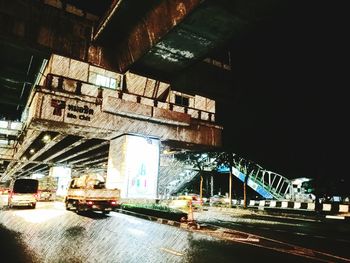 Illuminated road by bridge at night