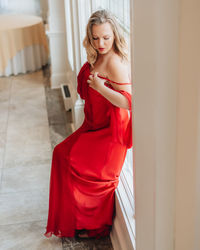 Young woman looking away while standing against red wall